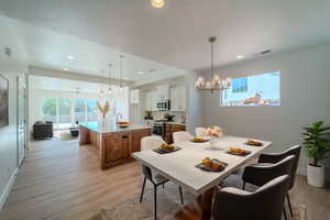 Dining room with sink, light hardwood / wood-style flooring, a textured ceiling, and a chandelier