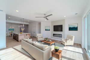 Living room featuring light hardwood / wood-style floors, sink, and ceiling fan with notable chandelier