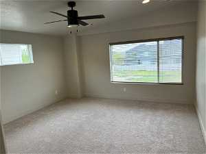 Unfurnished room featuring plenty of natural light, carpet floors, ceiling fan, and vaulted ceiling