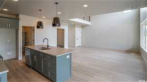 Kitchen with sink, light hardwood / wood-style flooring, dishwasher, and a kitchen island with sink