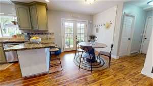 Kitchen featuring french doors, green cabinetry, dishwasher, tasteful backsplash, and hardwood / wood-style flooring