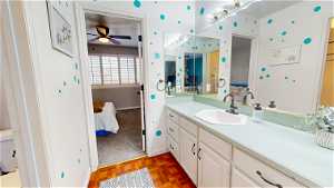 Bathroom featuring parquet flooring, oversized vanity, ceiling fan, and toilet