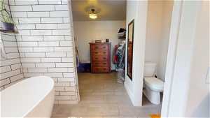 Bathroom featuring a bathing tub, toilet, and tile flooring