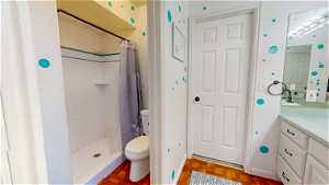 Bathroom with a shower with curtain, toilet, large vanity, and parquet flooring