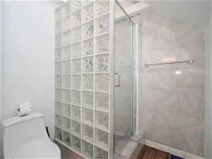 Bathroom with an enclosed shower, hardwood / wood-style flooring, and toilet