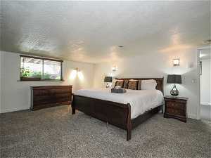 Bedroom with dark carpet and a textured ceiling