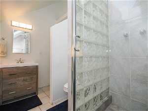 Bathroom with tile floors, oversized vanity, an enclosed shower, and toilet