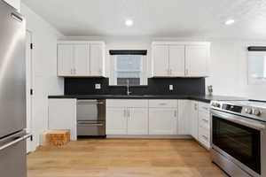 Kitchen with plenty of natural light, appliances with stainless steel finishes, white cabinets, and sink