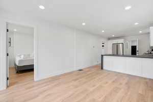 Kitchen featuring sink, white cabinetry, light wood-type flooring, and high end refrigerator