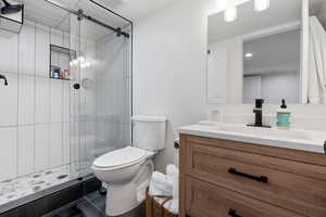 Bathroom with tile floors, vanity, toilet, and a shower with shower door