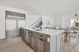 Kitchen with appliances with stainless steel finishes, sink, a center island with sink, and light wood-type flooring