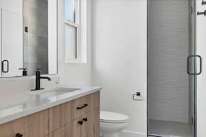 Bathroom with vanity, a shower with shower door, and toilet