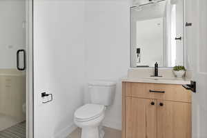 Bathroom featuring tile patterned floors, vanity, toilet, and a shower with door