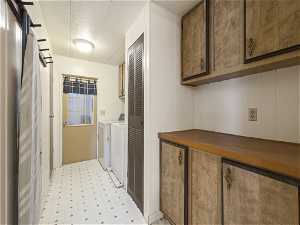 Laundry room featuring light tile flooring, washer and dryer, and cabinets