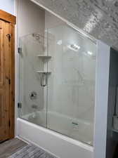 Bathroom featuring hardwood / wood-style floors and combined bath / shower with glass door