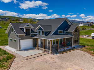 View of front of property featuring covered porch, a garage, and a front yard