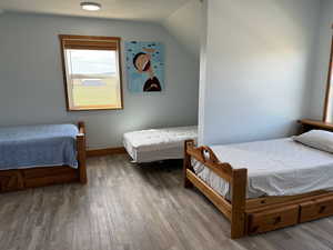 Bedroom with LVP flooring, lofted ceiling and balcony