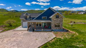 Exterior space with a garage, a mountain view, a front yard, and covered porch