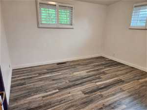 Empty room featuring plenty of natural light and dark hardwood / wood-style flooring