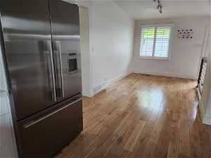 Kitchen with light hardwood / wood-style floors, high end fridge, and track lighting