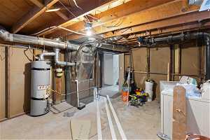 Basement with water heater, heating utilities, and washer and clothes dryer