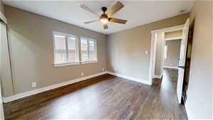 Empty room featuring ceiling fan and dark hardwood / wood-style floors