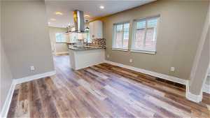 Kitchen with plenty of natural light, hardwood / wood-style floors, island range hood, and white cabinetry
