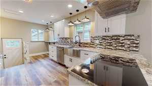 Kitchen featuring white cabinets, sink, dishwasher, backsplash, and hanging light fixtures