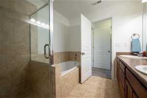 Bathroom featuring tile floors, separate shower and tub, and double sink vanity