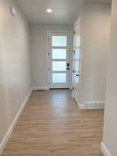 Doorway to outside with light hardwood / wood-style floors and a textured ceiling