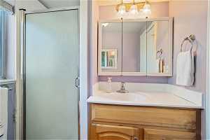 Bathroom with vanity with extensive cabinet space and a shower with door