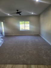 Living room featuring ceiling fan and dark hardwood / wood-style floors/ colored carpet