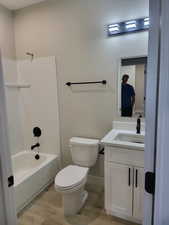 Full bathroom with bathtub / shower combination, wood-type flooring, toilet, and vanity