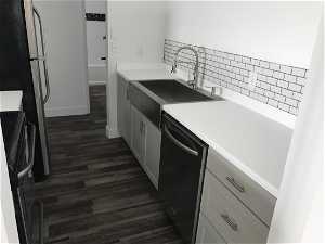 Kitchen with range, dark hardwood / wood-style floors, sink, tasteful backsplash, and dishwasher