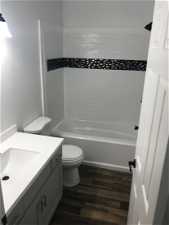 Full bathroom featuring tiled shower / bath combo, wood-type flooring, vanity, and toilet