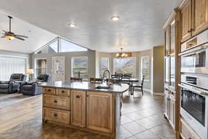 Kitchen featuring vaulted ceiling, light hardwood / wood-style flooring, a healthy amount of sunlight, and a kitchen island with sink