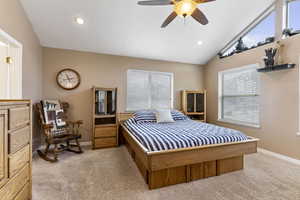 Carpeted bedroom featuring lofted ceiling, multiple windows, and ceiling fan