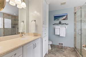 Bathroom featuring a shower with door, vanity, toilet, and tile floors