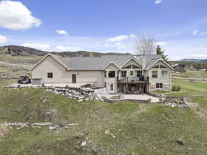 Back of house with a patio, a deck with mountain view, and a lawn