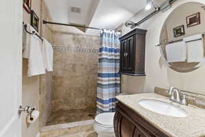 Bathroom with a shower with shower curtain, toilet, tile floors, and vanity