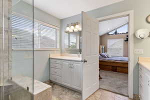 Bathroom featuring vaulted ceiling, a wealth of natural light, vanity, and tile flooring