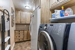 Laundry Room featuring washing machine and dryer, cabinets, tile floors, and a textured ceiling