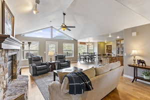 Living room with light hardwood / wood-style flooring, vaulted ceiling, plenty of natural light, and a stone fireplace