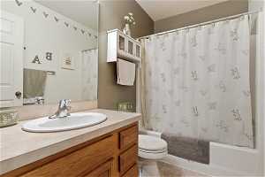 Full bathroom featuring tile flooring, oversized vanity, toilet, and shower / tub combo with curtain