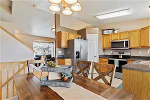 Kitchen featuring stainless steel appliances, lofted ceiling, sink, an inviting chandelier, and light tile floors