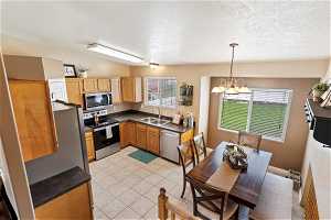Kitchen featuring decorative light fixtures, stainless steel appliances, light tile flooring, sink, and a chandelier