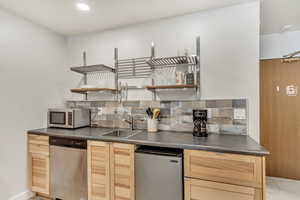 Kitchen featuring tasteful backsplash, light tile flooring, light brown cabinetry, sink, and appliances with stainless steel finishes