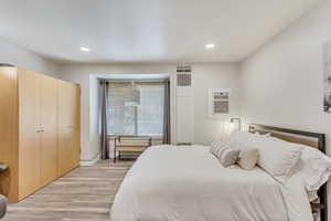 Bedroom featuring light hardwood / wood-style floors, a closet, and an AC wall unit