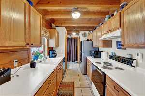 Kitchen with beamed ceiling, sink, light tile flooring, white electric range, and wooden ceiling