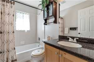 Full bathroom with toilet, oversized vanity, and shower / bath combination with curtain